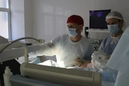 Операционная: врач с ассистентом во время вмешательства на венах