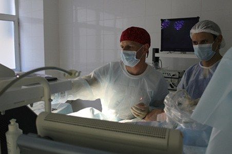 Операционная: врач с ассистентом во время вмешательства на венах